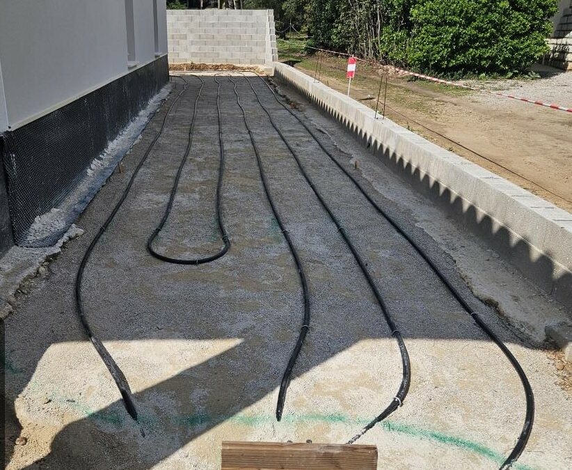 Boucles de capteurs géothermiques en attente de raccordement le long d’un mur, chantier Kraft Géothermie